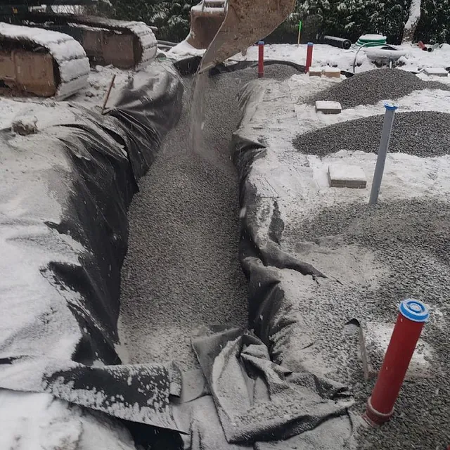 Grävskopa fyller grus i diken